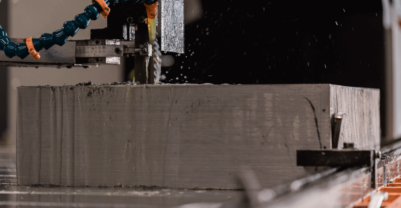 Fotografia de um bloco de aço a ser cortado pelo serrote de um equipamento industrial
