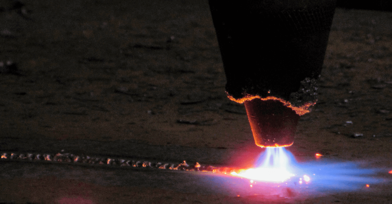Detalhe de uma chapa de aço a ser oxicortada. A fotografia mostra o contacto da chama com a chapa.