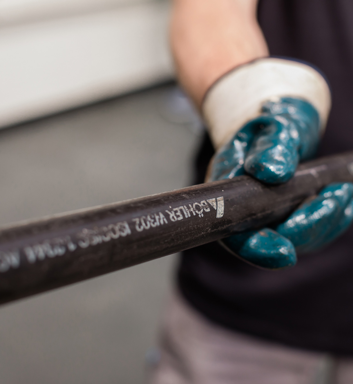 Uma mão com uma luva de segurança segura um varão de aço